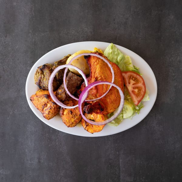 A white plate with grilled chicken, beef, shrimp, onions, and a side salad.
